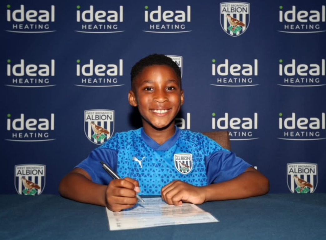 Young football player signing professional academy contract after training with Soccer Inclusion Birmingham coaching program